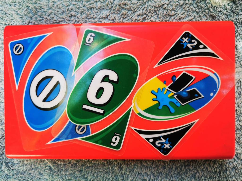 UNO im Test: drei verschiedene Karten liegen auf einer roten Box.