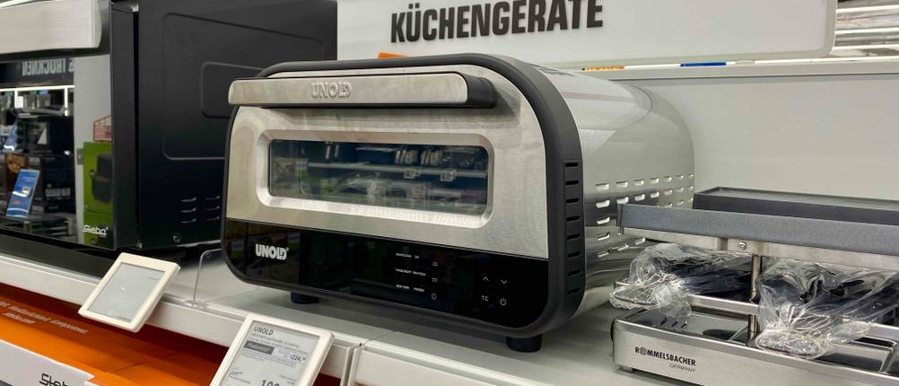 Pizzaofen (elektrisch) getestet: Ein Gerät von schräg vorne auf einem Verkaufsregal mit Preisschild davor.