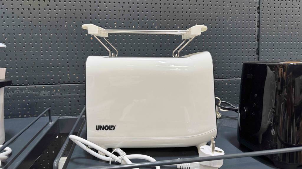 Ein Toaster steht zum testen in einem Regal neben einem schwarzen.