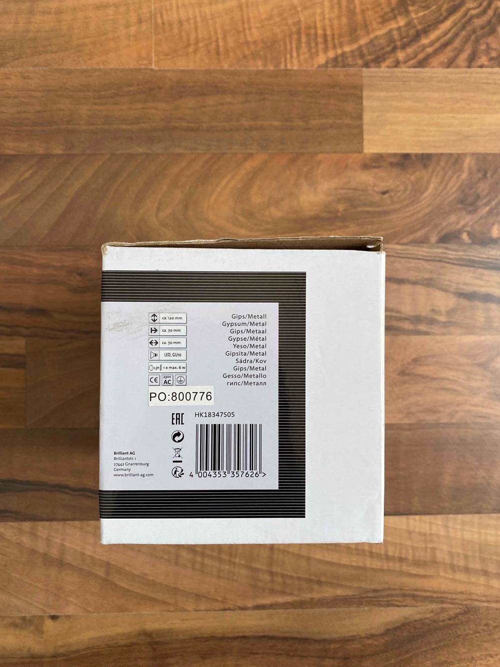 Nahaufnahme der Rückseite der Verpackung einer getesteten Unterbauleuchte auf einer Holzfläche.