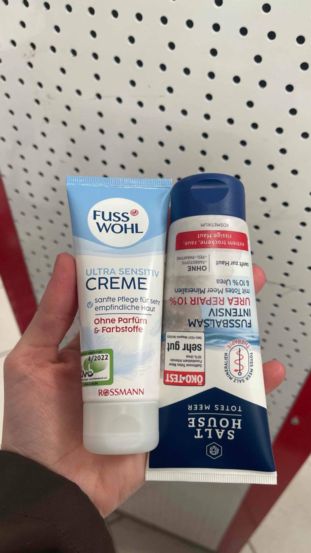 Urea-Fußcreme im Test: Zwei verschiedene Tuben liegen nebeneinander in einer Hand.