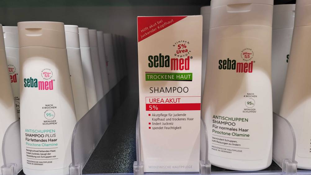 Eine Packung des getesteten Urea-Shampoos steht in einem Verkaufsregal neben anderen Produkten.