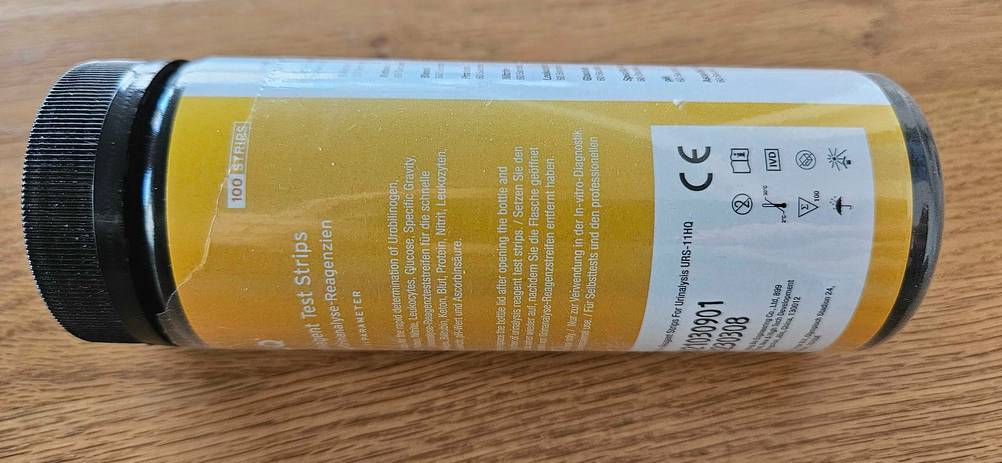 Auf einem Holztisch befindet sich eine Verpackung von getesteten Urinteststreifen.