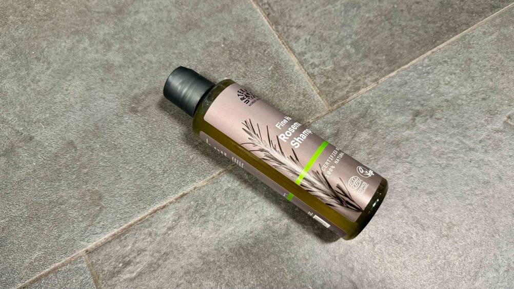 Auf einem Fließenboden liegt eine Flasche Urtekram-Shampoo im Test.