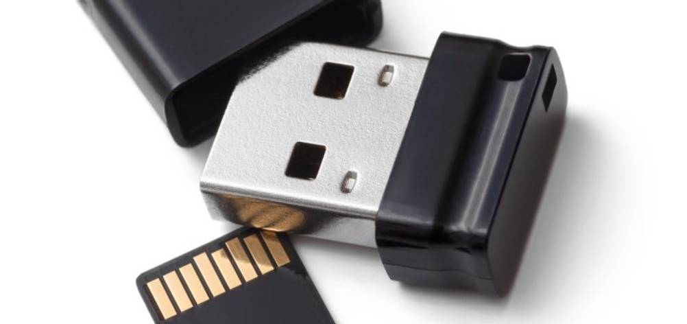 Detailansicht eines getesteten Nano-USB-Sticks mit 256 GB auf weißem Hintergrund. Daneben liegt eine SD-Speicherkarte. 