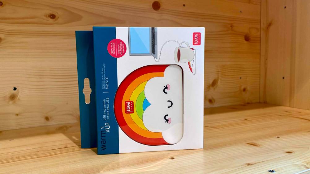 Ein originalverpackter USB-Tassenwärmer im Test in einem Holzregal.