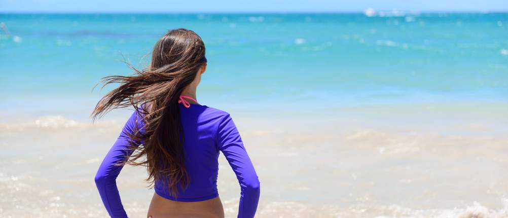 UV-Shirt-Damen-Test: Eine Frau mit einem UV-Shirt steht am Strand.