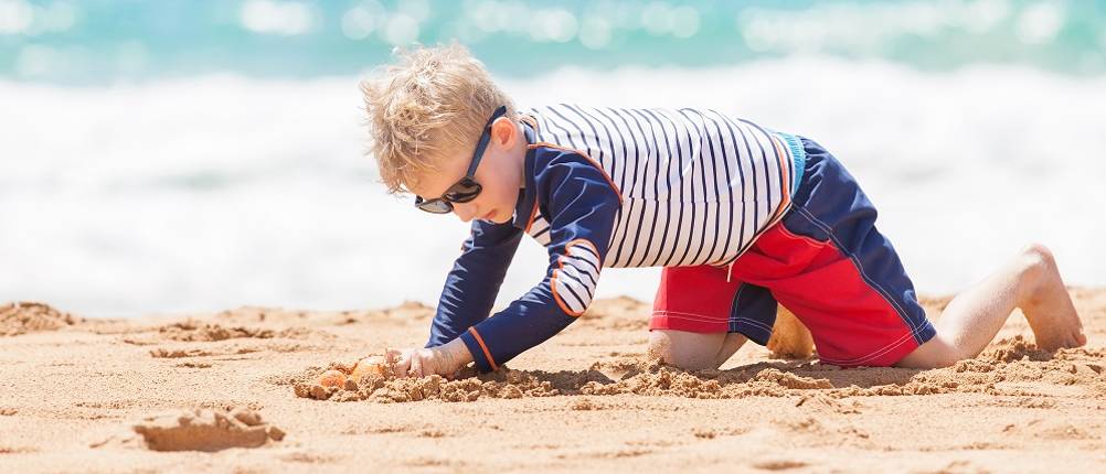 UV-Shirt-Kinder-Jungen-Test: Ein Junge spielt mit einem UV-Shirt an einem Strand.