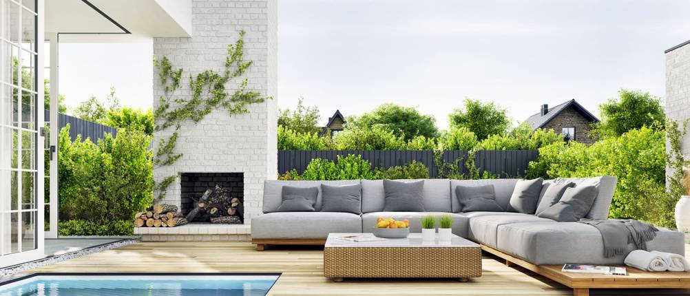 Terrasse mit Pool und Gartenmöbeln, auf denen graue Sitzpolster liegen.