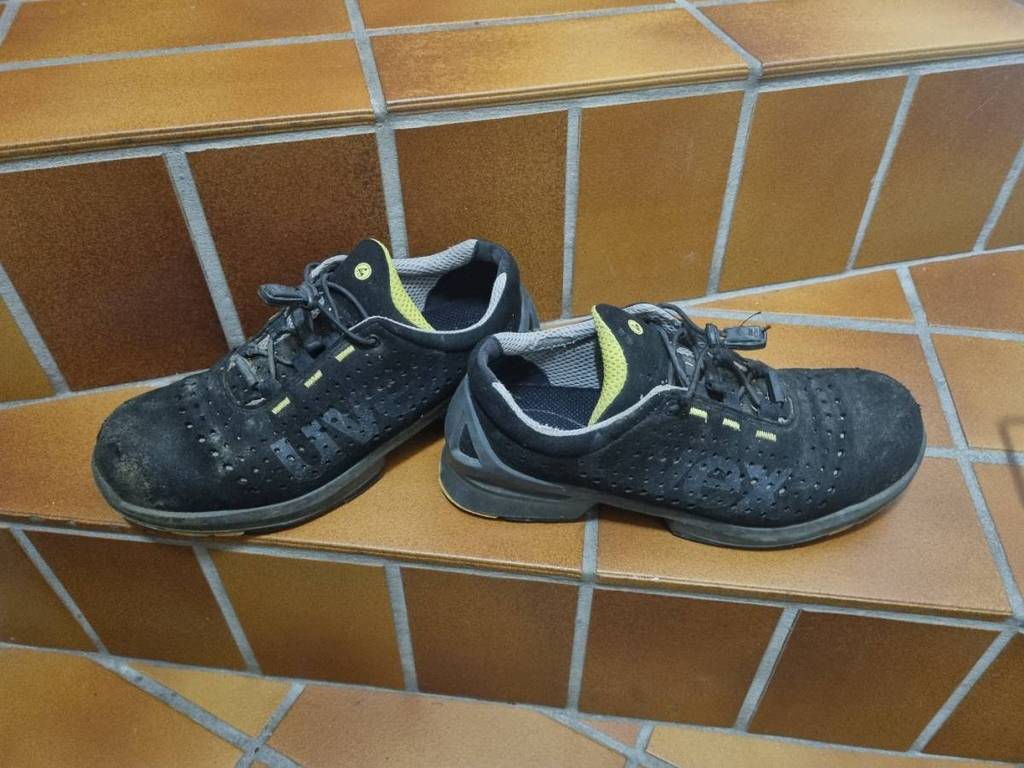 Im Test: schwarze Sicherheitsschuhe von Uvex mit gelben Elementen und Zug-Schnürung befindet sich auf einer braunen Treppe.