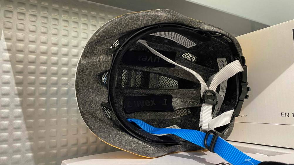 Ein Uvex-Fahrradhelm ist zu Test bereit: Ansicht auf die Belüftungskanäle und die Befestigungs-Gurte.