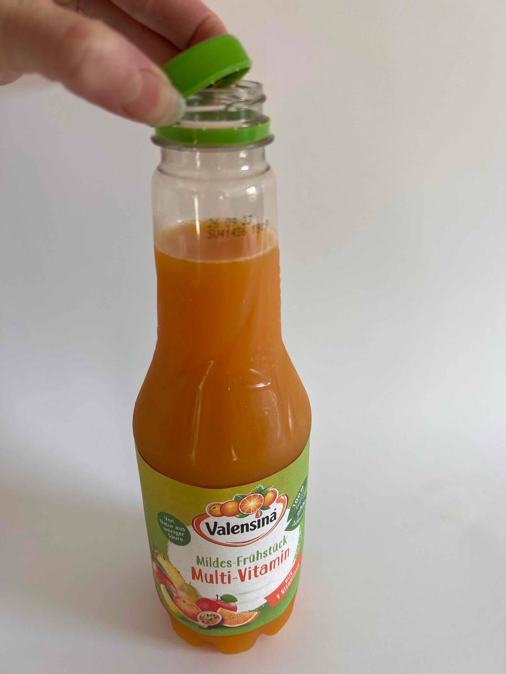 Hand öffnet eine Flasche Multivitaminsaft zum testen.