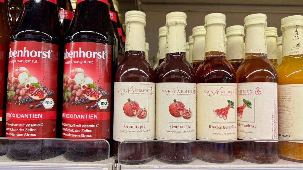Bio-Granatapfelsaft im Test: Mehrere Flaschen stehen neben weiteren Fruchtsäften auf einem Verkaufsregal.