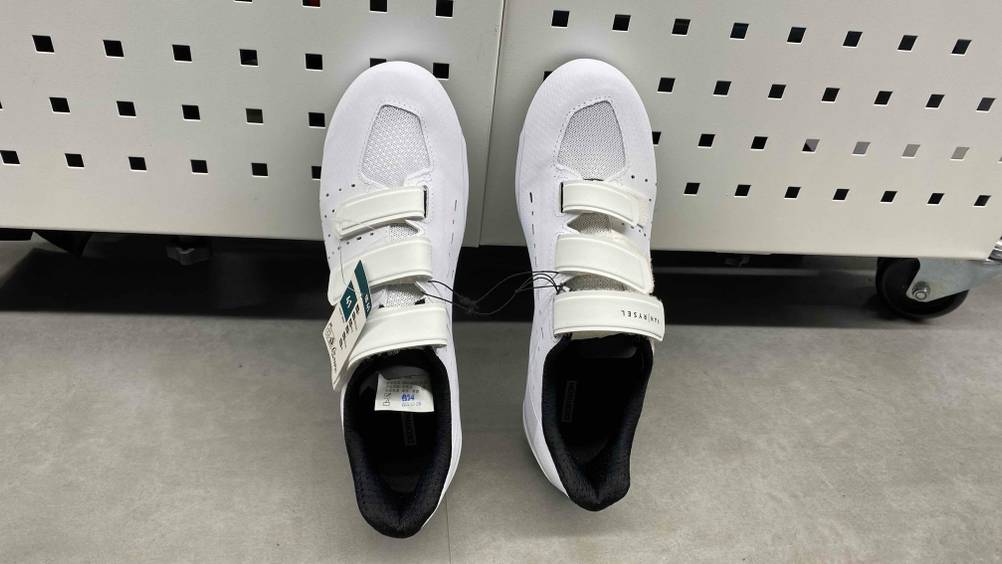 Im Test: Ein Paar Rennradschuhe lehnt mit der Ferse am Boden an einer Metallbox.