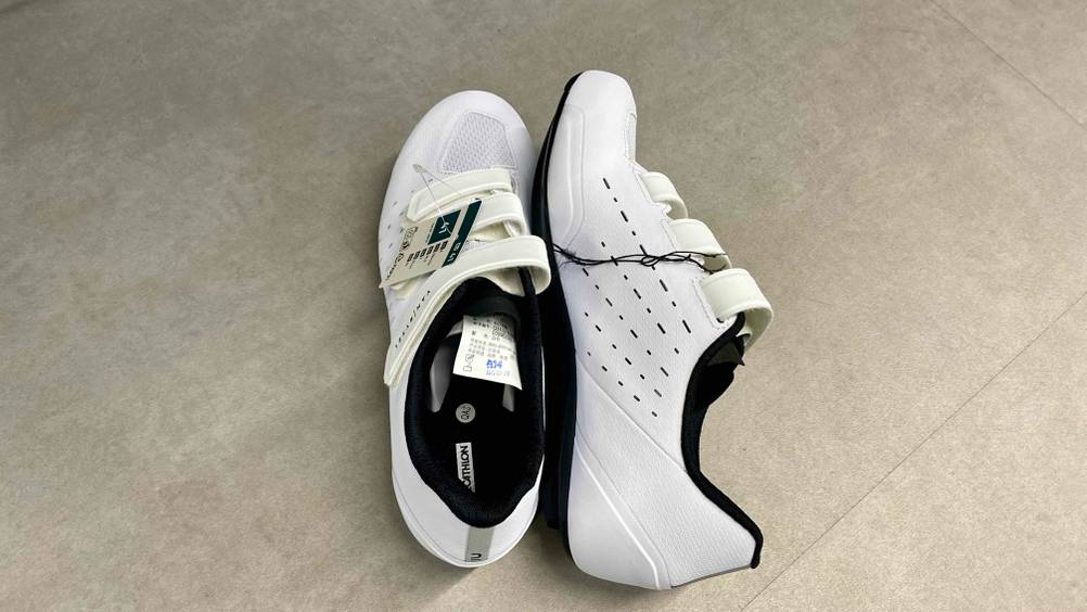 Rennradschuhe getestet: Ein Paar nebeneinander einer stehend einer auf der Seite liegend auf einem grauen Boden.