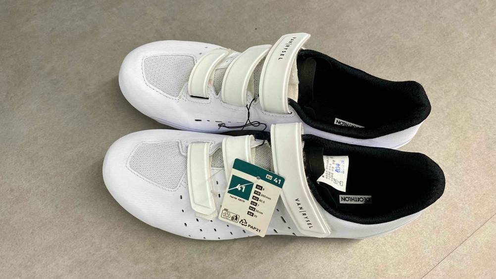 Ein Paar getestete Rennradschuhe von oben stehen nebeneinander horizontal auf einem grauen Boden.