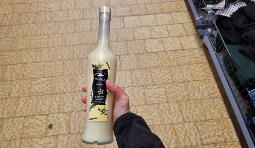 Eine Hand hält eine Flasche des getesteten Vanille-Likörs hoch.