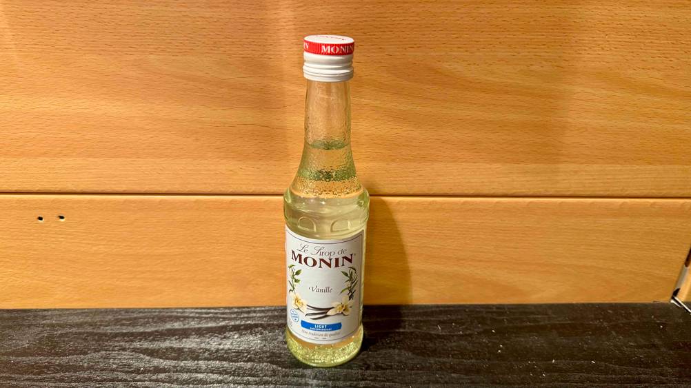 Vanille-Sirup-Test: Eine Flasche von schräg oben vor einer Holzfläche.