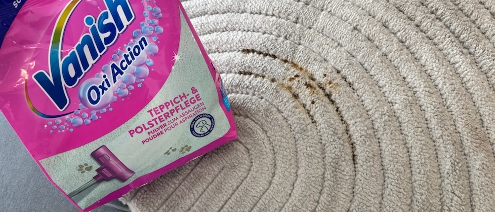 Vanish-Teppichreiniger steht auf einem Teppich mit einem frischen Kaffeefleck 