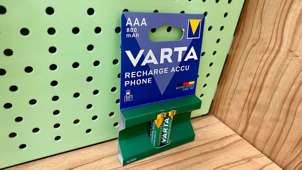 AAA-Akku getestet: Eine Packung mit 2 Akkus leicht seitlich vor einem grünen Lochblech und Holz.