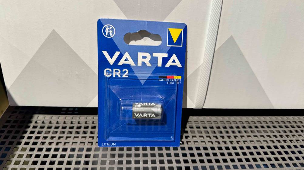 Die getestete Varta-Batterie vor einer hellen Fläche auf einem Gitter.