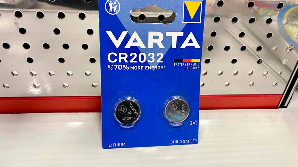 CR2032-Batterien getestet: Eine Packung mit 2 Batterien lehnt an einem silbernen Lochblech.