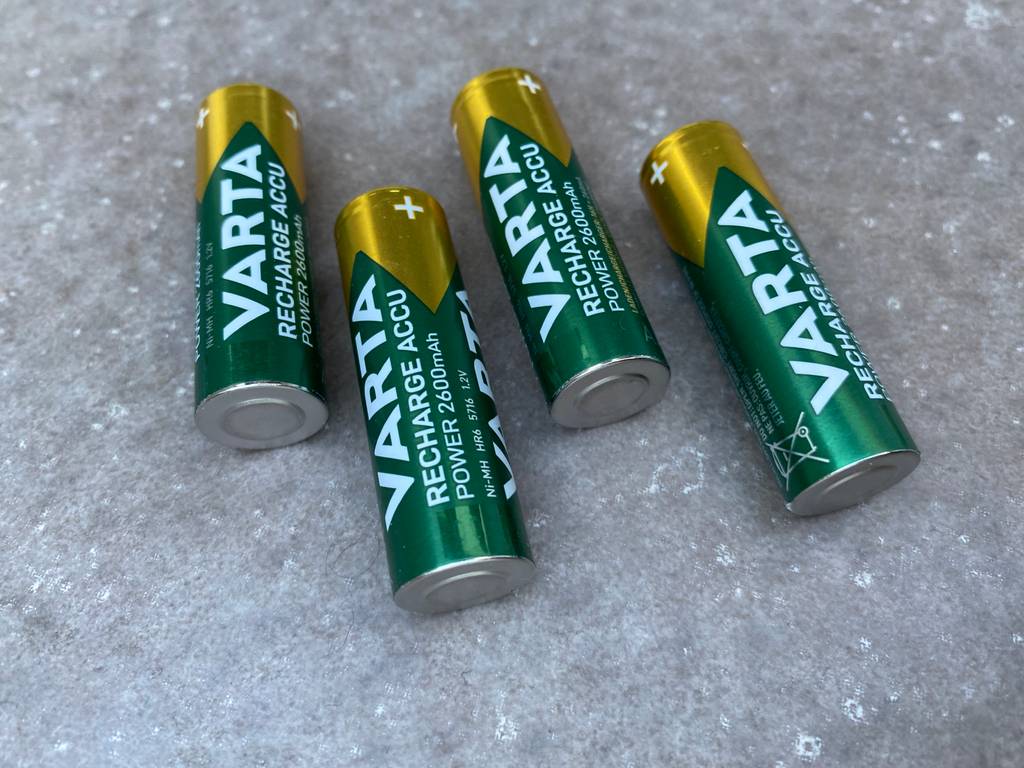  Varta AA-Akkus liegen auf grauem Hintergrund. Die Batterien sind grün,gelb.