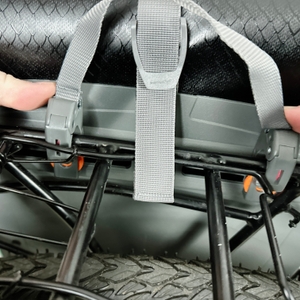 Zwei Hände lösen die obere Befestigung der Vaude-Aqua-Back-Tasche vom Gepäckträger. Die Haken werden nach oben gezogen.