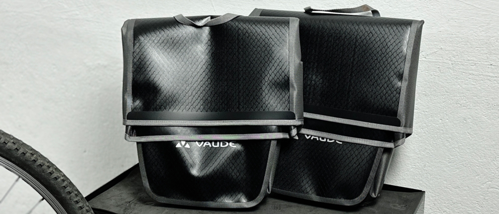 Zwei Vaude-Aqua-Back-Fahrradtaschen stehen nebeneinander auf einem Regal. Die Taschen sind geschlossen und stehen frei.