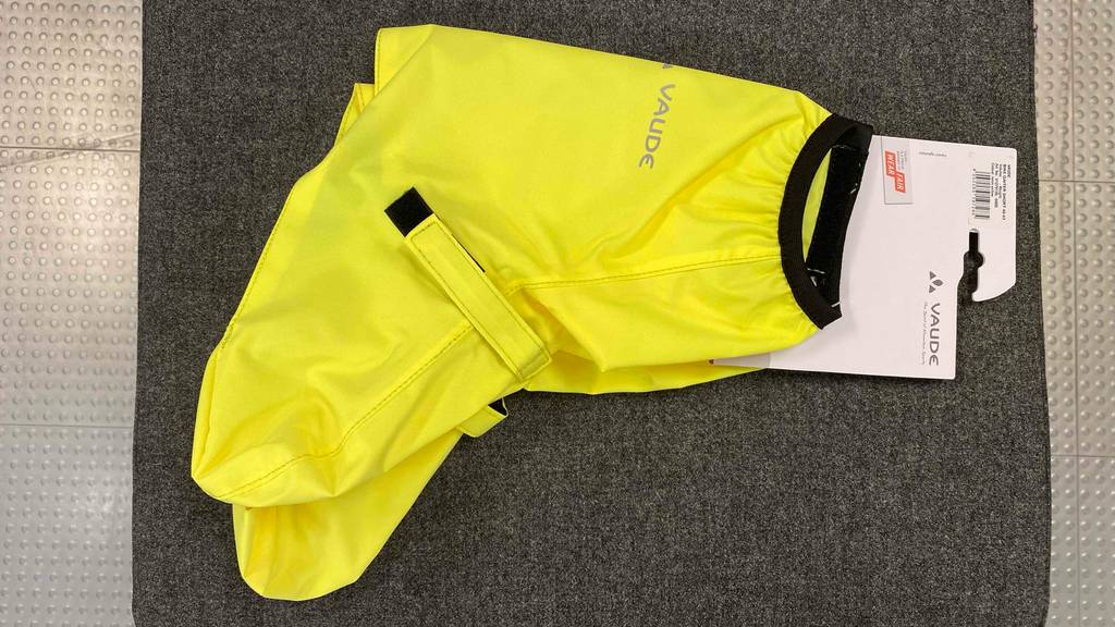 Gelb leuchtende, getestete Fahrrad-Überschuhe von Vaude liegen, mit Fokus auf den Hauptverschluss und das Gummiband am Saum, auf einer grauen Matte.