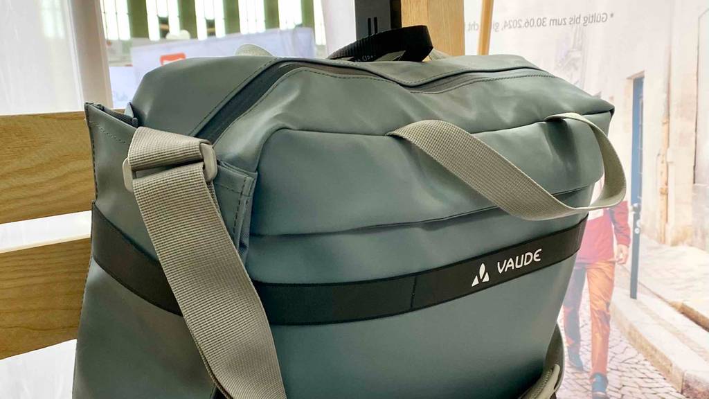 Detailansicht der hellgrauen Büro-Fahrradtasche im Test, mit Fokus auf den Schultergurt und die Tragegriffe.
