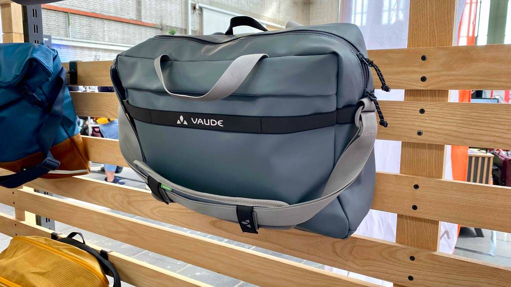 Büro-Fahrradtaschen-Test: eine graue Fahrradtasche der Marke Vaude an einem Holz-Ausstellungsregal im Geschäft.
