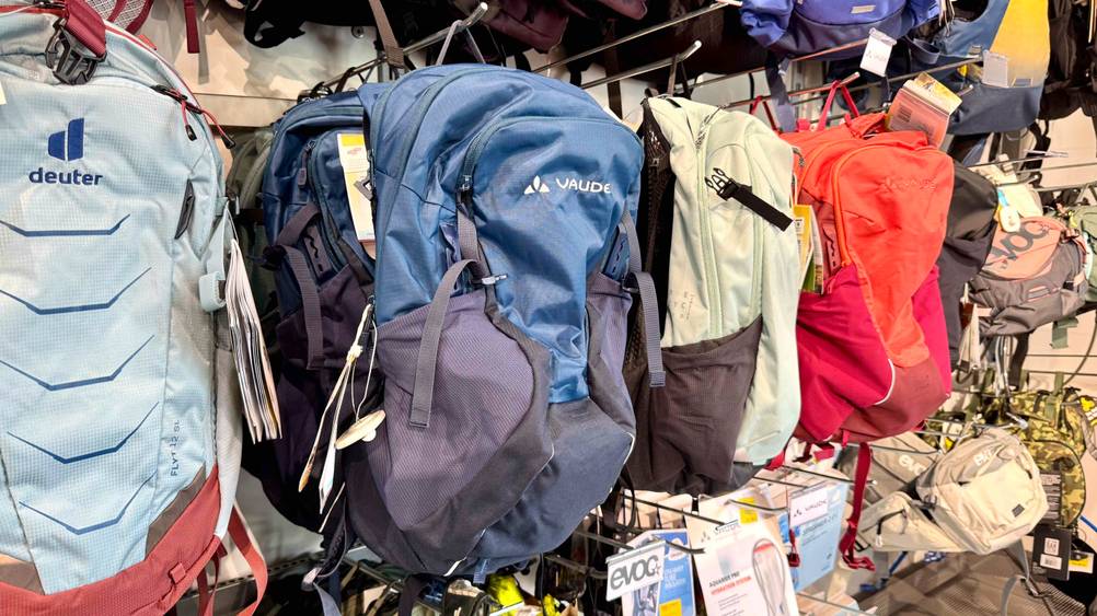 Mehrere Vaude-Rucksack im Test in einem Verkaufsregal neben anderen Marken hängend.