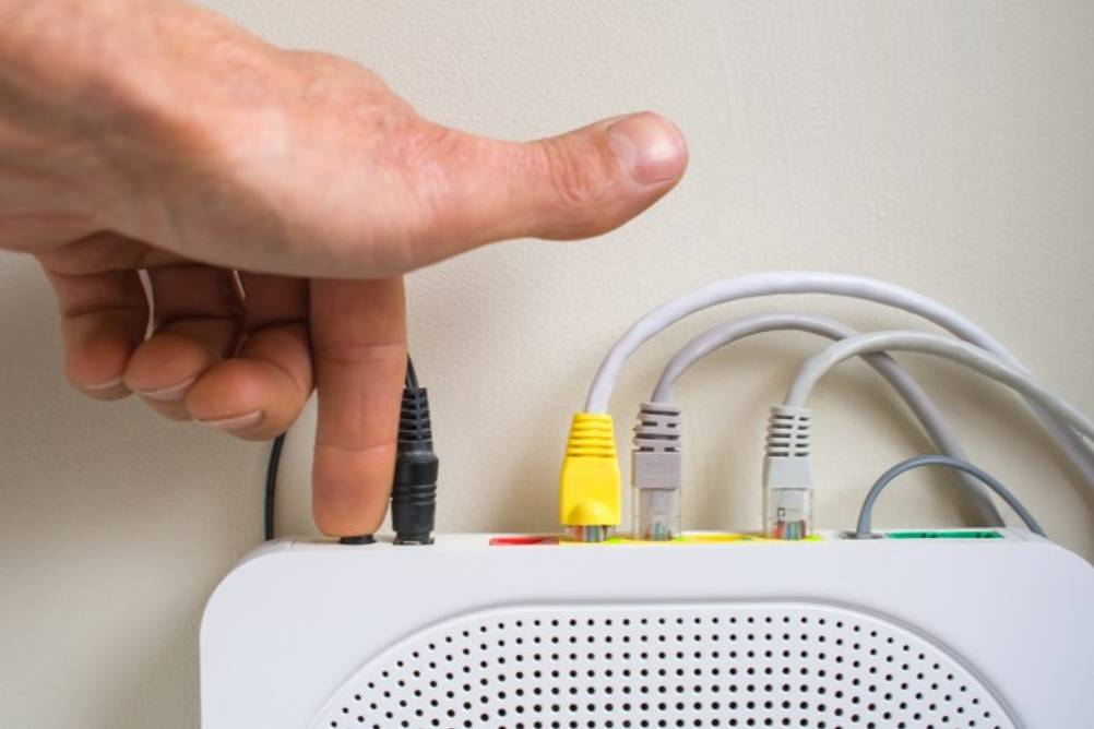 Mann drückt WPS-Taste an einem getesteten Telekom-Router