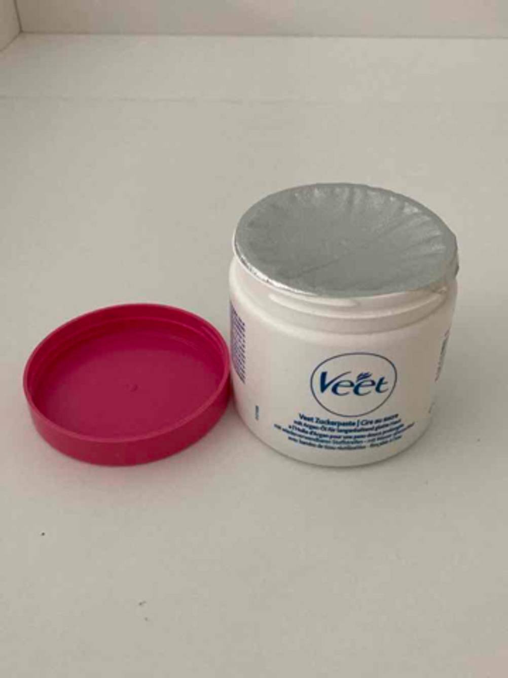 In einer VEET-Dose befindet sich die luftdicht verpackte getestete Zuckerpaste auf einer beigefarbenen Oberfläche.