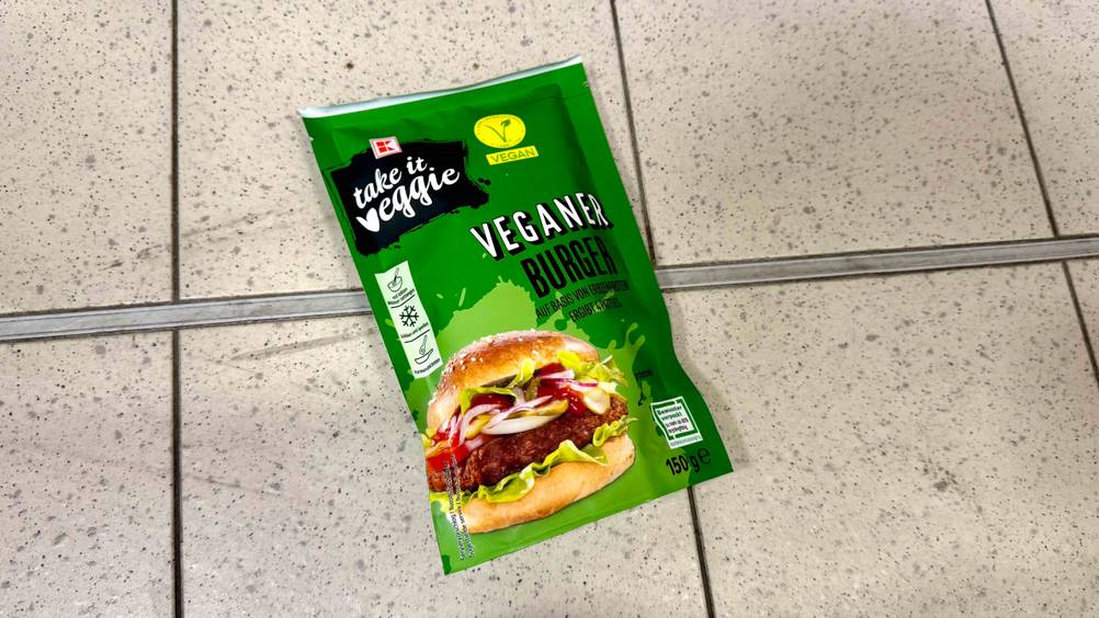 Auf einem Fliesenboden liegt eine Packung der getesteten veganen Burger-Patties.