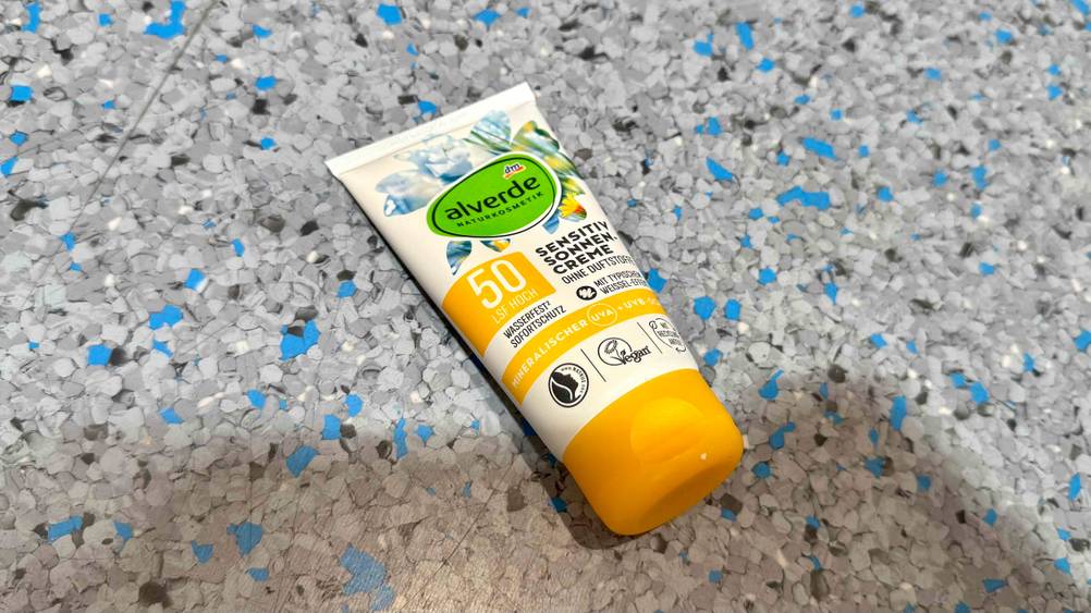 Auf einem grau-blauen Boden liegt eine Tube der getesteten veganen Sonnencreme.