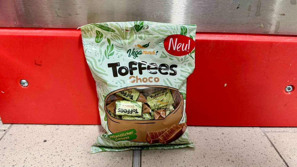 Eine Packung der getesteten veganen Süßigkeiten vor einer roten Leiste am Boden.