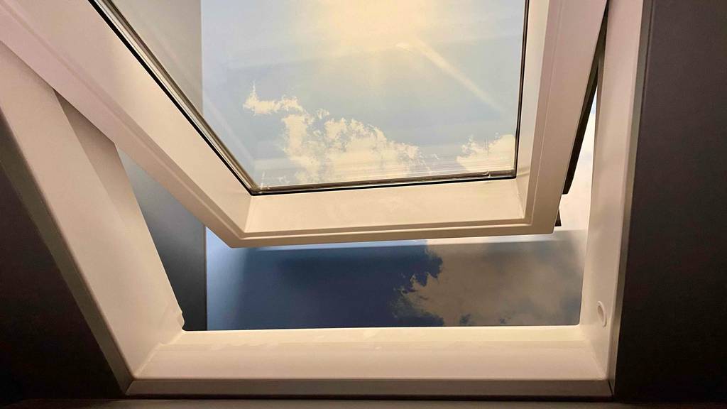 Im Test: Dachfenster. Nahaufnahme eines geöffneten Dachfensters im weißen Schwingrahmen-Design.