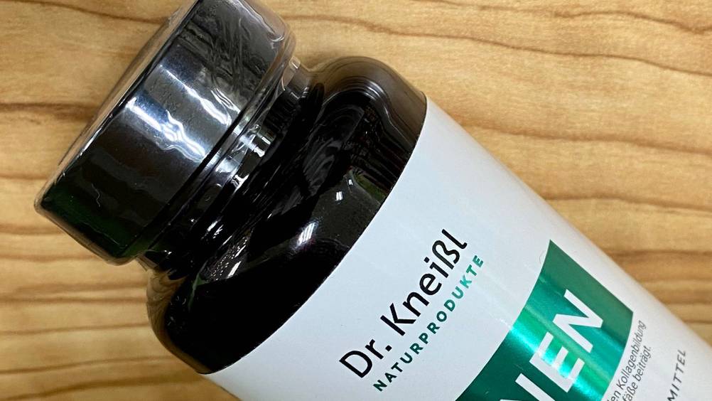 Nahaufnahme des Logos und des Verschlusses einer Flasche der getesteten Venen-Tabletten auf einer Holzfläche.
