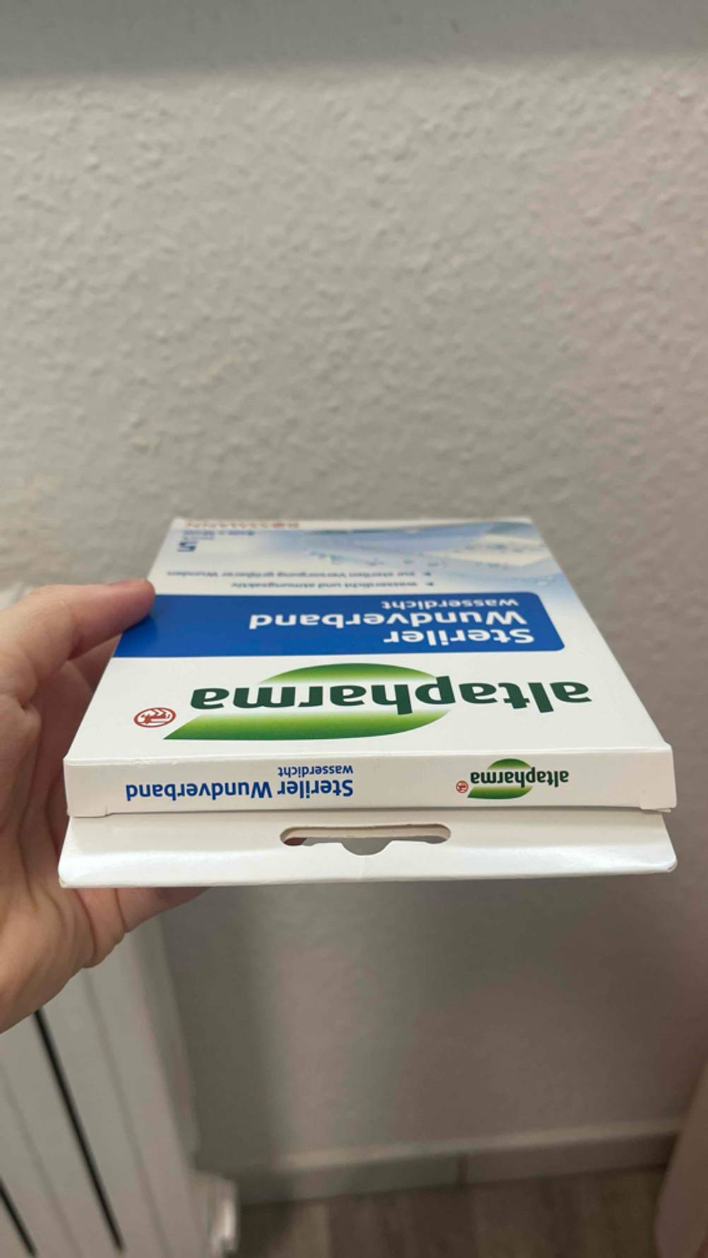 Im Test: Eine Hand hält eine Packung Verband mit der Oberseite nach vorn.