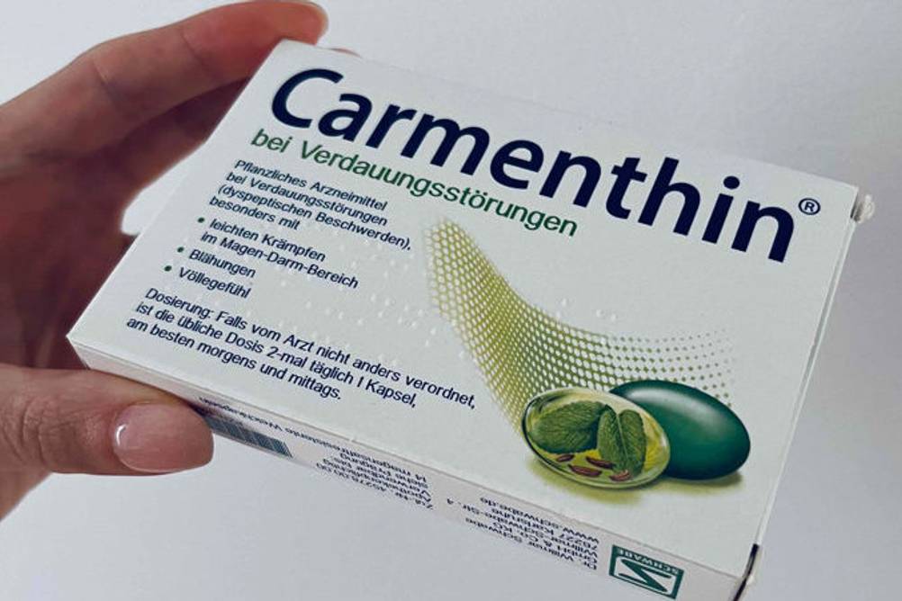 Eine Hand hält die getesteten Carmenthin-Kapseln fest.