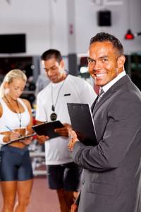 Vereinssoftware-Test: Ein Mann im Anzug schließt einen Vertrag mit zwei Mitarbeitenden eines Fitness-Studios ab.