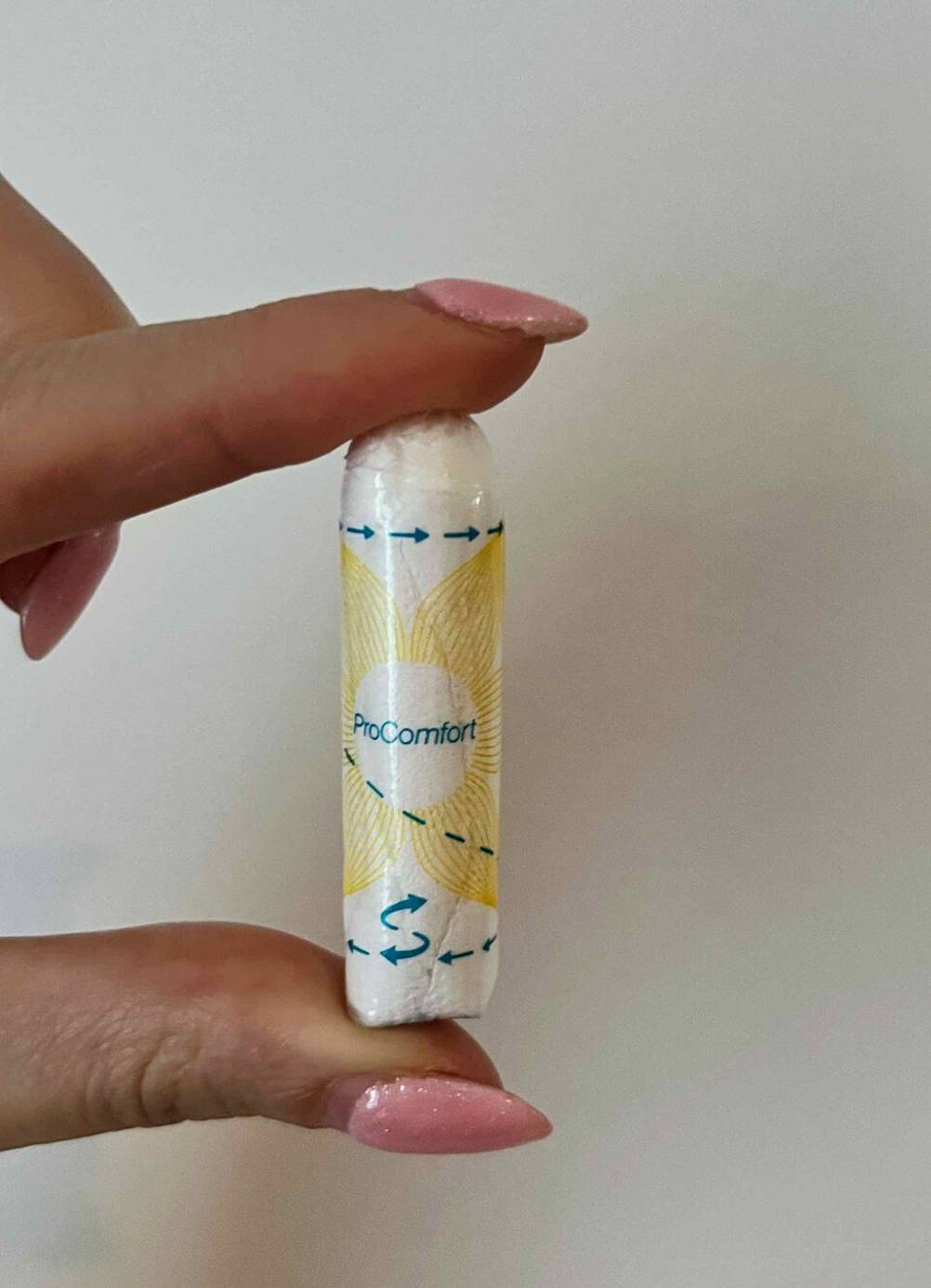 Hand hält ein getestetes Tampon ProComfort der Marke o.b. vor einer weißen Wand.