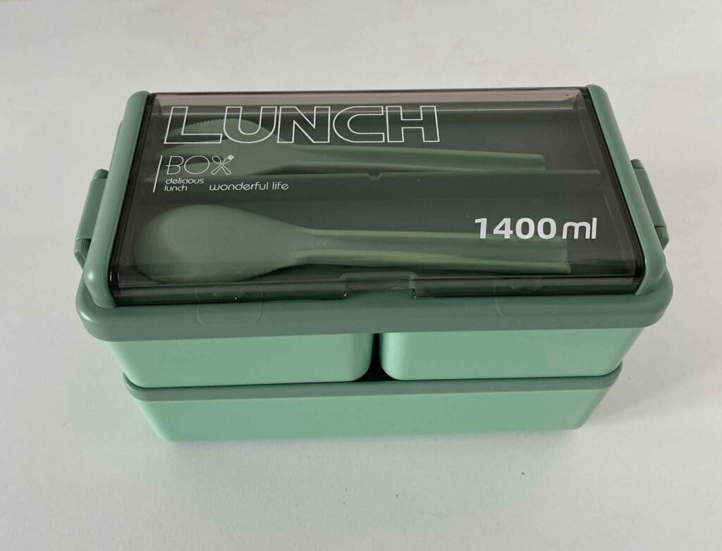 Zwei getestete Bento-Boxen mit Besteck stehen übereinander auf einer weißen Fläche.