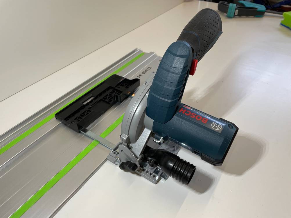 Auf einer Sägeschiene ist eine Bosch-Handkreissäge im Test inklusive Messvorrichtung positioniert.