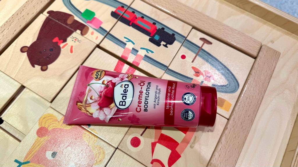 Eine Tube mit BALEA Bodylotion im Test liegt auf einem hölzernen Kinderpuzzle.