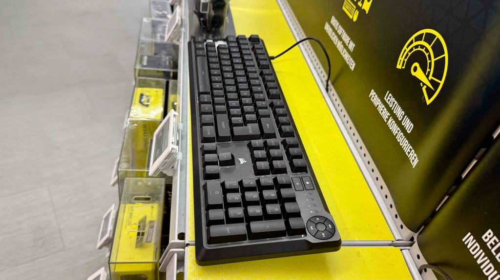 Seitenansicht der schwarzen, getesteten Corsair-Tastatur, die auf einem gelben Ausstellungsregal über den Preisschildern befindet.
