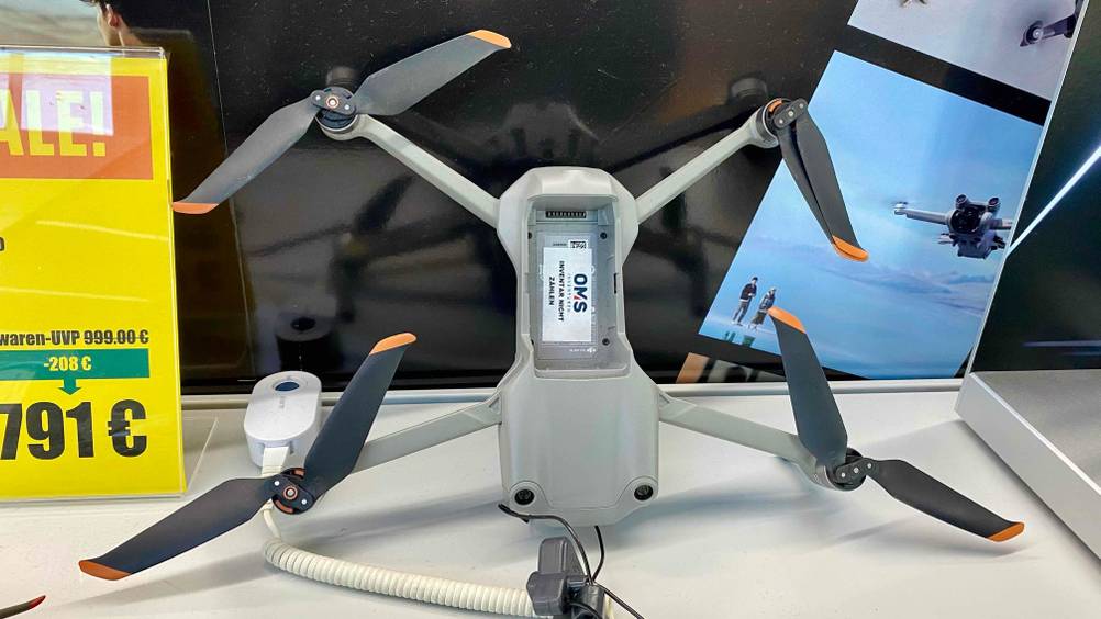 DJI-Drohnen im Test: Nahaufnahme einer hellgrauen Kamera-Drohne, mit Fokus auf die Aussparung für den Akku, die in einem Geschäft ausgestellt ist.