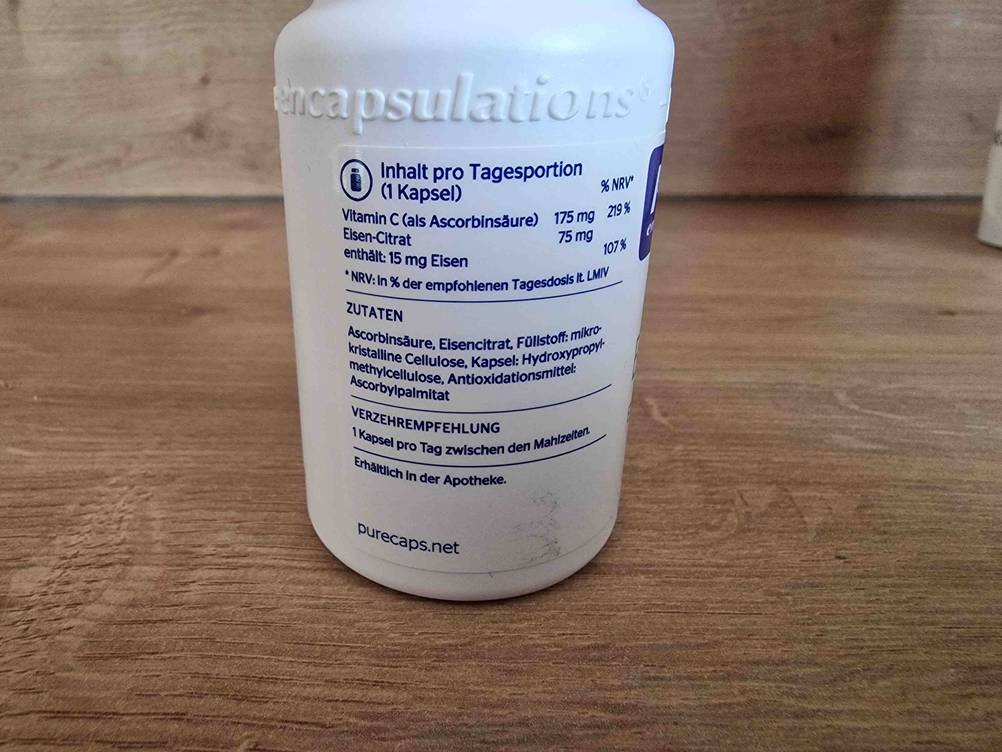 Eisenpräparat im Test: weißer Kunststoffbehälter mit Produktinformationen auf einer Holzfläche.